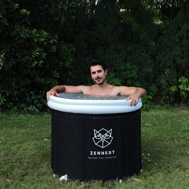 Man sitting in the Zennest Pro Cylinder 90 with its white double rim, filled with ice, on a garden lawn
