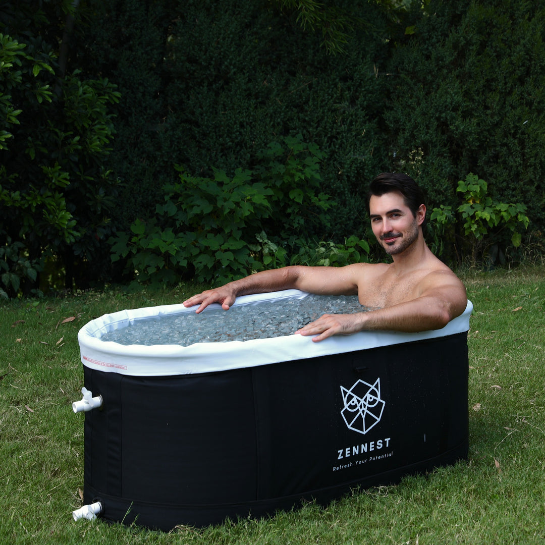 Man sitting in the Zennest Pro Oval 140 with its white liner rim, filled with ice, on a garden lawn