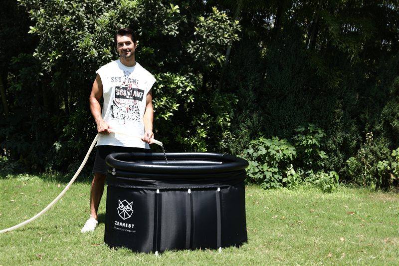 A man filling a Zennest Oval 150 with a garden hose